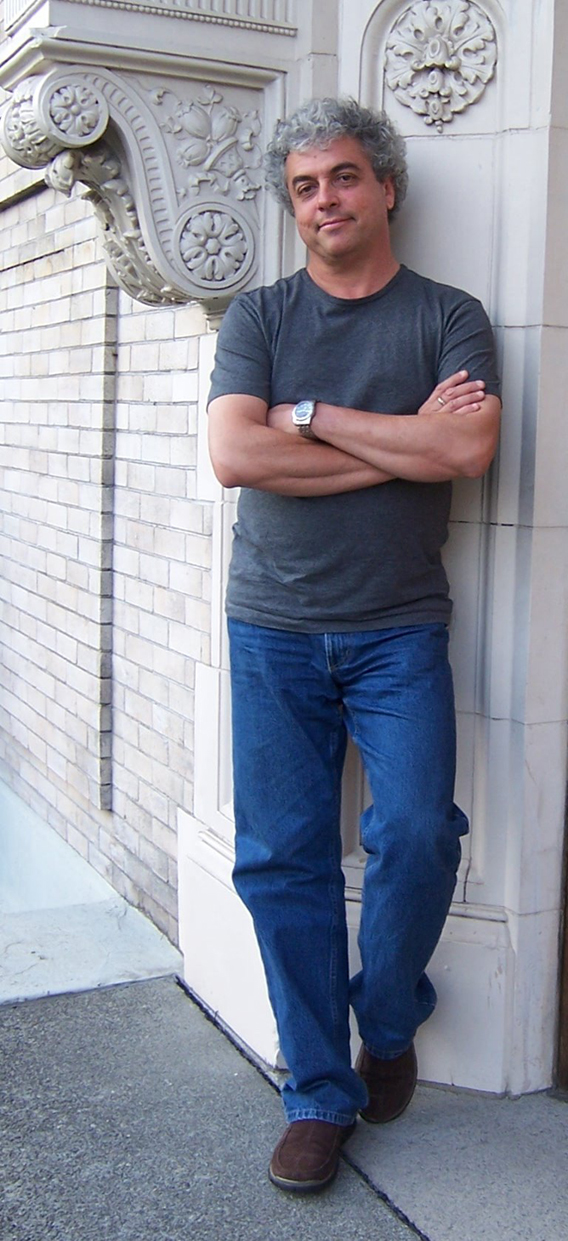 Jovino Santos leaning up against an old building, with friendly smile.
